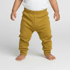 Mustard yellow sweatpants on a gray background