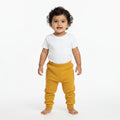 Mustard yellow sweatpants on a gray background