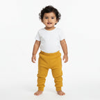 Mustard yellow sweatpants on a gray background