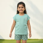 Green sleeveless top and floral shorts set on a light gray background